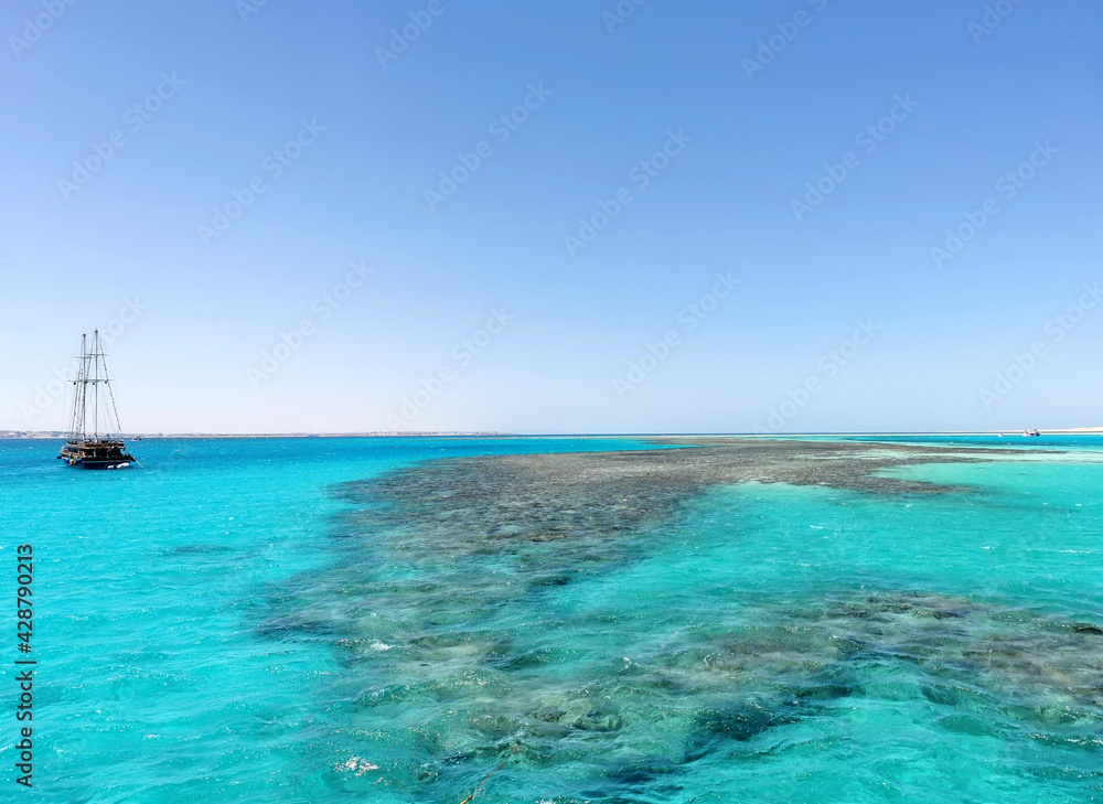 The Red Sea reefs seascape with ship silhouette on the horizon. Travel and recreation in Egypt, sea excursion above the reef for snorkeling and beautiful nature