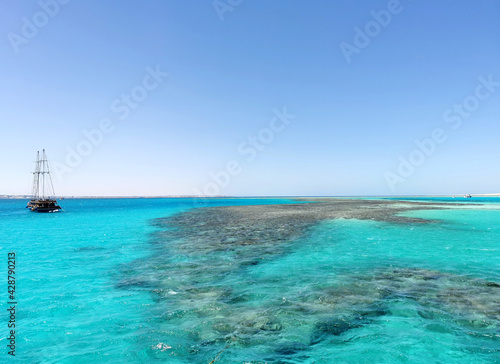 The Red Sea reefs seascape with ship silhouette on the horizon. Travel and recreation in Egypt, sea excursion above the reef for snorkeling and beautiful nature