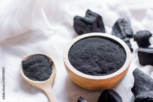 The black charcoal powder in the wooden cup was placed on a white cloth.
