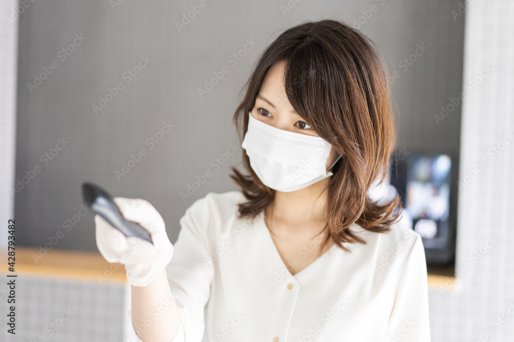 感染拡大防止のためにお客様の体温を計測するスタッフ 感染拡大防止のためにお客様の体温を計測するスタッフ