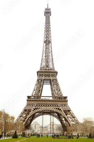Tourist gathering under Tour de Eiffel on a cloudy day.