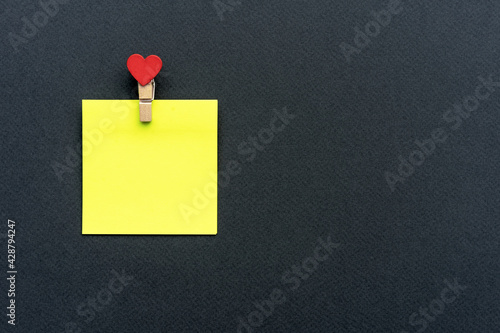 Yellow sticker with a clothespin on a black background.