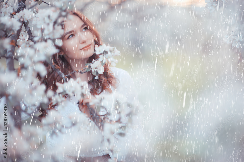 young girl spring portrait in a blooming garden, springtime happiness, rain weather in the park in April young girl spring portrait in a blooming garden, springtime happiness, rain weather in the park in April