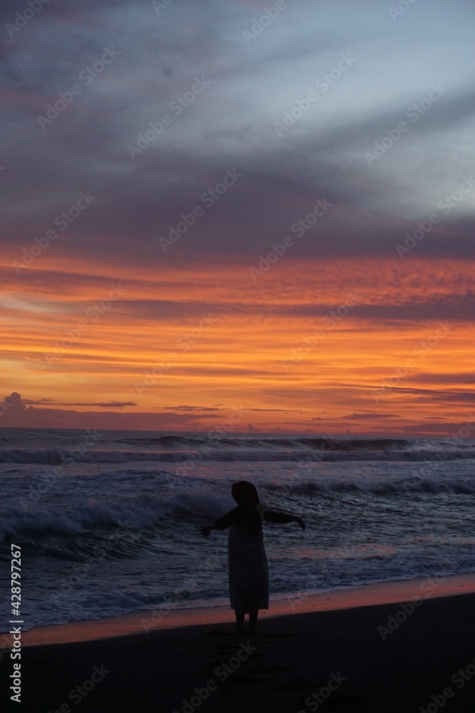 silhouette of person walking on the beach at sunset silhouette of person walking on the beach at sunset