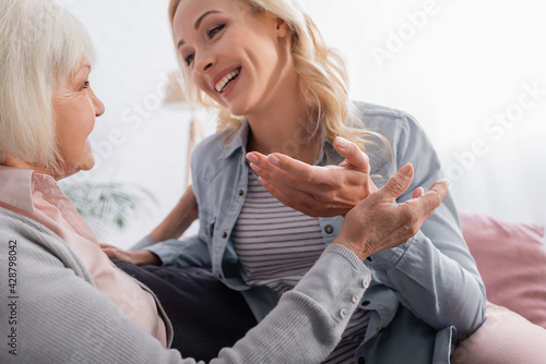 Fototapeta Naklejka Na Ścianę i Meble -  Senior woman sitting near smiling daughter talking on blurred background