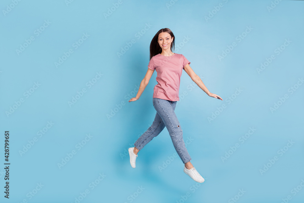 Full length profile side photo of charming happy positive girl jump up walk empty space isolated on blue color background