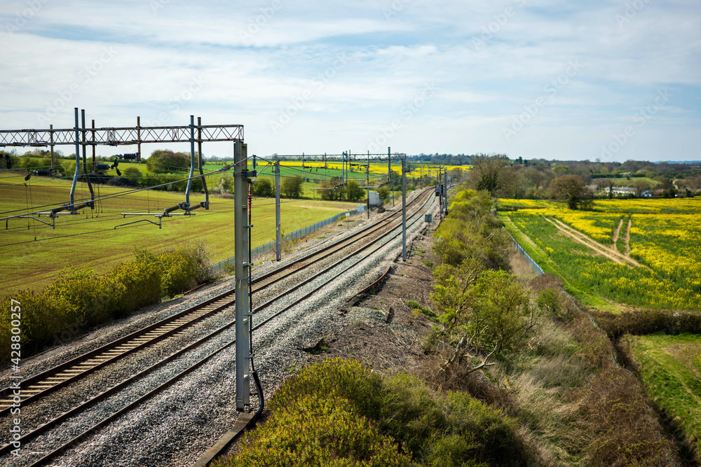 uk train railroad next to rapeseed field in bloom day view in england