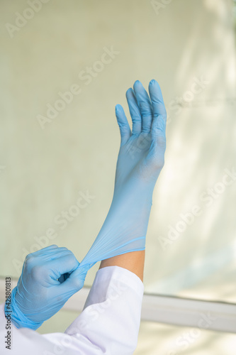 Doctor or nurse putting on blue nitrile surgical gloves, professional medical safety and hygiene for surgery. Coronavirus Vaccine concept. Concept of fight against coronavirus.