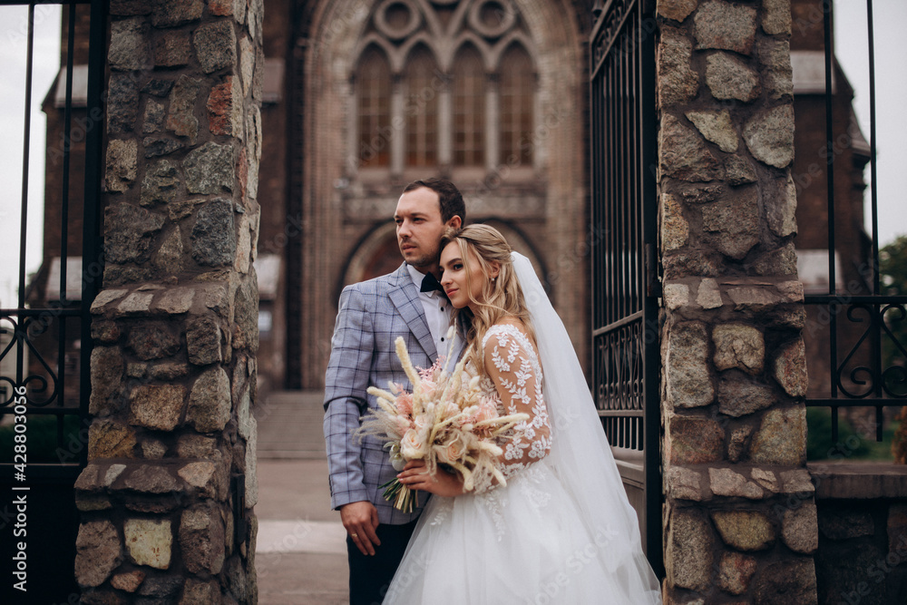 Beautiful newlywed couple near old catholic church Beautiful newlywed couple near old catholic church