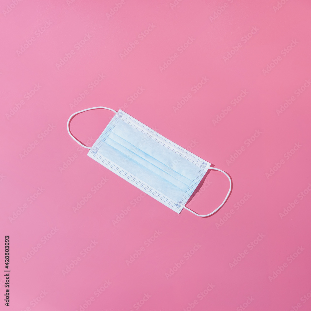 One medical face mask on a pink background. Isometric concept in the style of minimalism. One medical face mask on a pink background. Isometric concept in the style of minimalism.