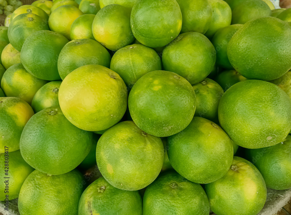 Green oranges on the market to buy, Thai oranges are among the juiciest of oranges with a yellowish-green peel and bright orange flesh