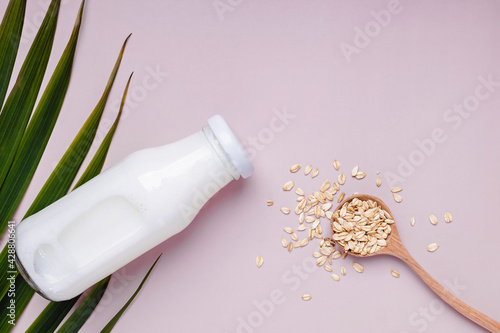Bottle with daity free oat milk and dry oats in the spoon.
