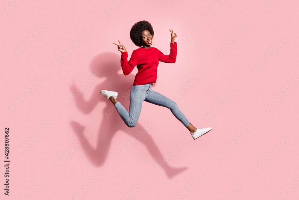 Full length body size view of attractive trendy cheerful girl jumping showing v-sign running isolated over pink pastel color background