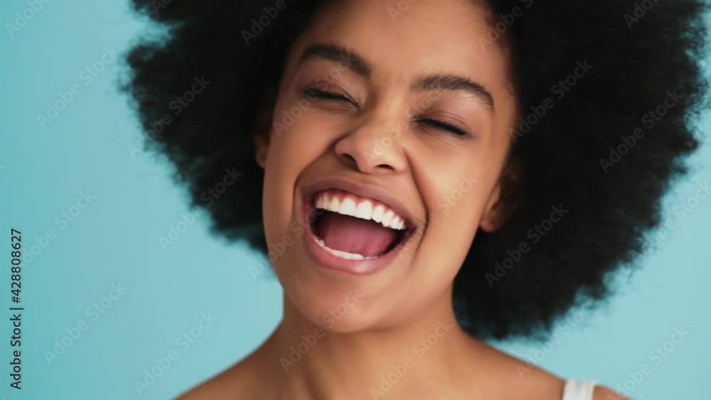 The slow motion shot of a smiling black woman shaking her head in different directions in the studio The slow motion shot of a smiling black woman shaking her head in different directions in the studio