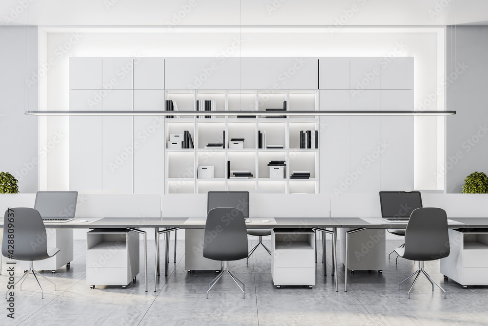 Monochrome style spacious coworking office with white office cabinet behind stylish work places Monochrome style spacious coworking office with white office cabinet behind stylish work places