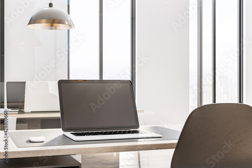 Blank laprop screen on wooden table in spacious sunny office work place. 3D rendering