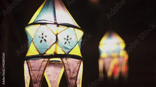 Traditional Colourful Sri Lankan vesak lanterns sway in wind slow mo on black night background. Ceylon style design idea. Beautiful DIY paper lanterns with lights and unique 3D flower designs