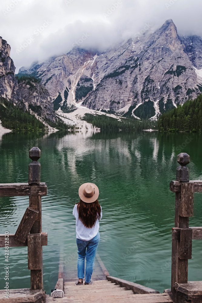 Woman traveler in a hat standing at the bank of beautiful lake