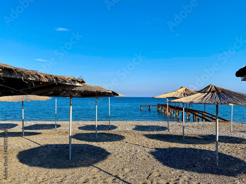 Empty beach with reed umbrellas, no one on the beach. Beautiful blue sky, sea, sand, hot weather. A beach without travelers and tourists. Quarantine due to covid-19 coronavirus.