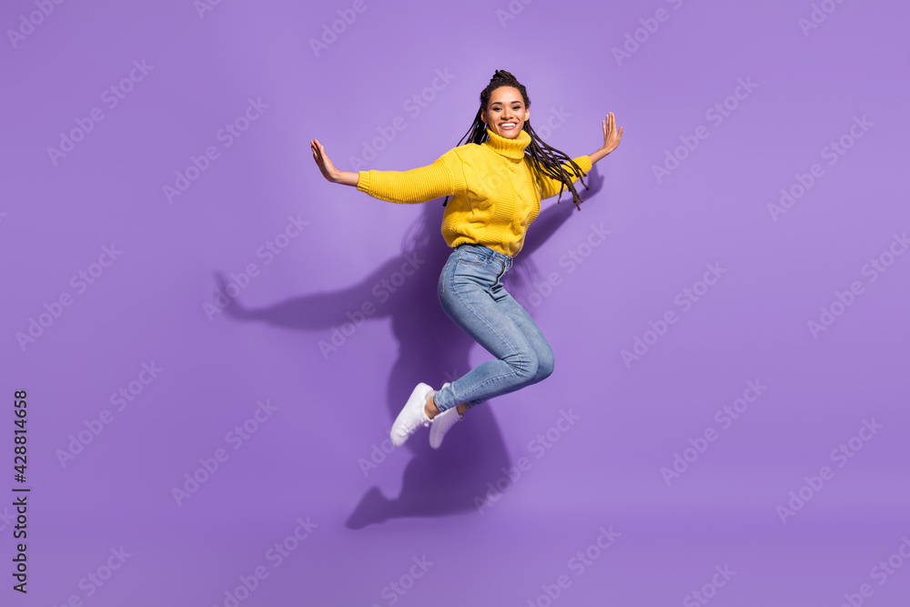 Full size profile photo of optimistic brunette lady dance wear yellow sweater jeans sneakers isolated on purple color background