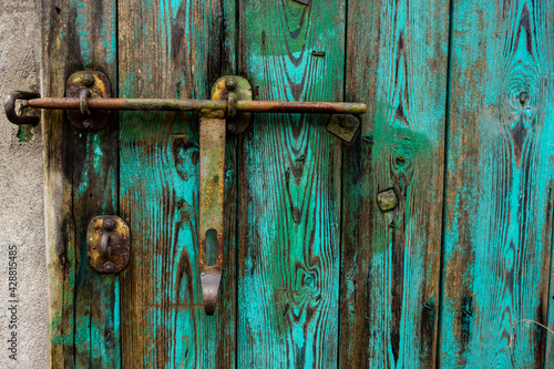 Old, green, wooden doors to farm buildings, with steel fittings. Poor lighting conditions