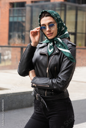 Portrait of a stylish young woman in a scarf and a leather jacket in the open air