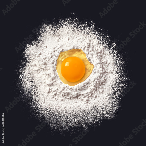 Egg in flour. Dough preparation. Black background. View from above.
