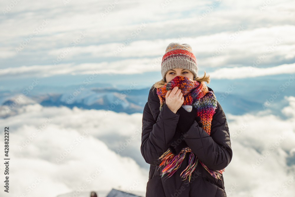 Portrait of adventure woman walking in winter in the mountains, clouds above the mountains background