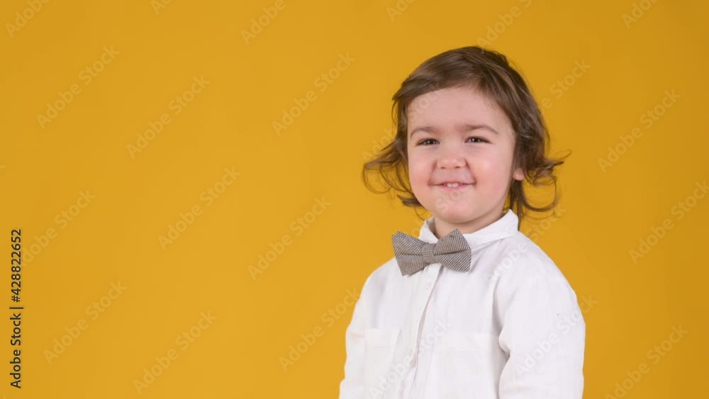 Laughing cute baby portrait. Funny little boy laughs and looks at the camera isolated on yellow studio background. People childhood lifestyle concept Laughing cute baby portrait. Funny little boy laughs and looks at the camera isolated on yellow studio background. People childhood lifestyle concept