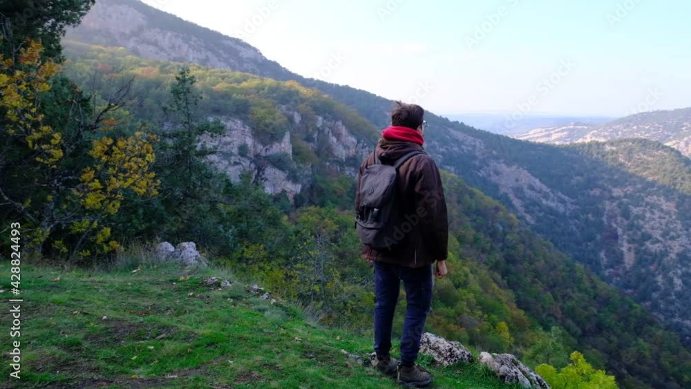 Traveler Guy walks in Picturesque Place of Wildlife and Looks at Autumn Landscape and Beautiful Mountains. Travel Concept Active People on the Way to Victory Traveler Guy walks in Picturesque Place of Wildlife and Looks at Autumn Landscape and Beautiful Mountains. Travel Concept Active People on the Way to Victory