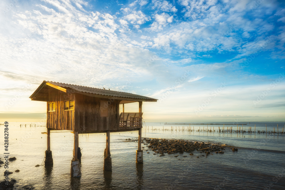 A small wood hut in the sea with blue sky during sunrise time.