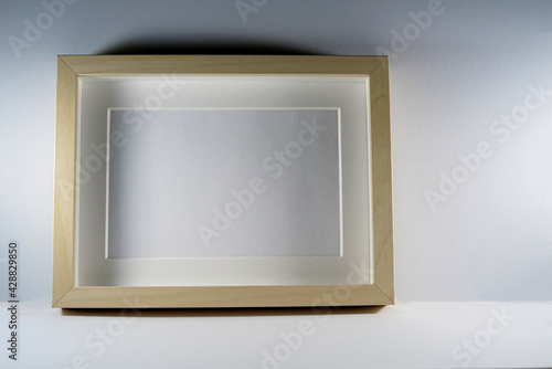 Picture frame with wooden frame photographed frontally in the studio with shadows