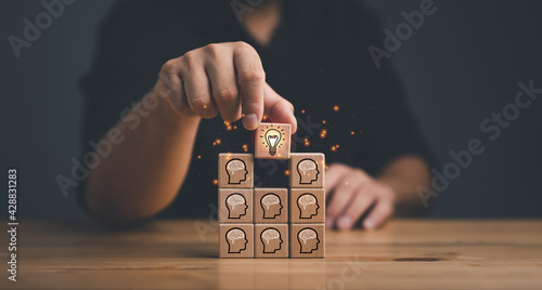 brainstorming creative idea and innovation. Hand putting over wooden cube block with light bulb icon on many people together having an idea symbolized by icons on cubes. photo