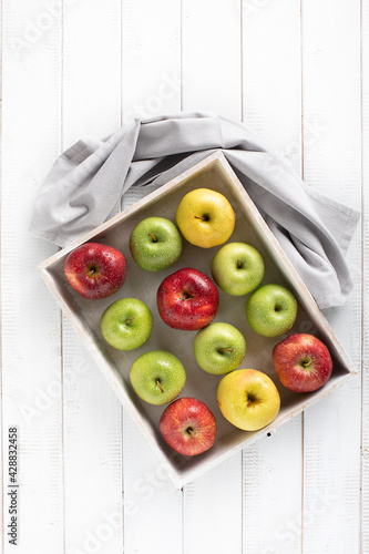 Colorful apples in a wood tray top view