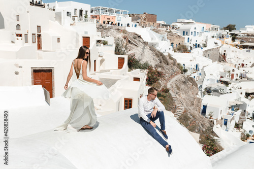 The couple is sitting on the roof in Santorini, hugging and laughing © Oleksandr