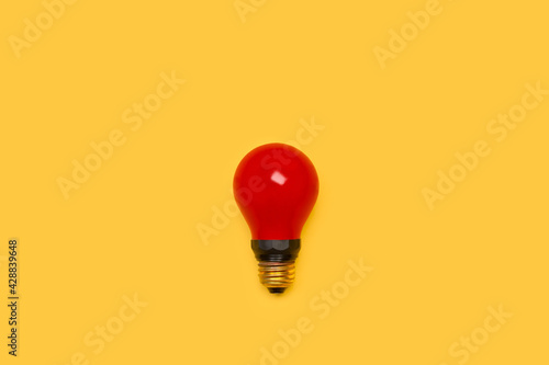 Bombilla de luz roja sobre un fondo amarillo liso y aislado. Vista superior. Copy space photo