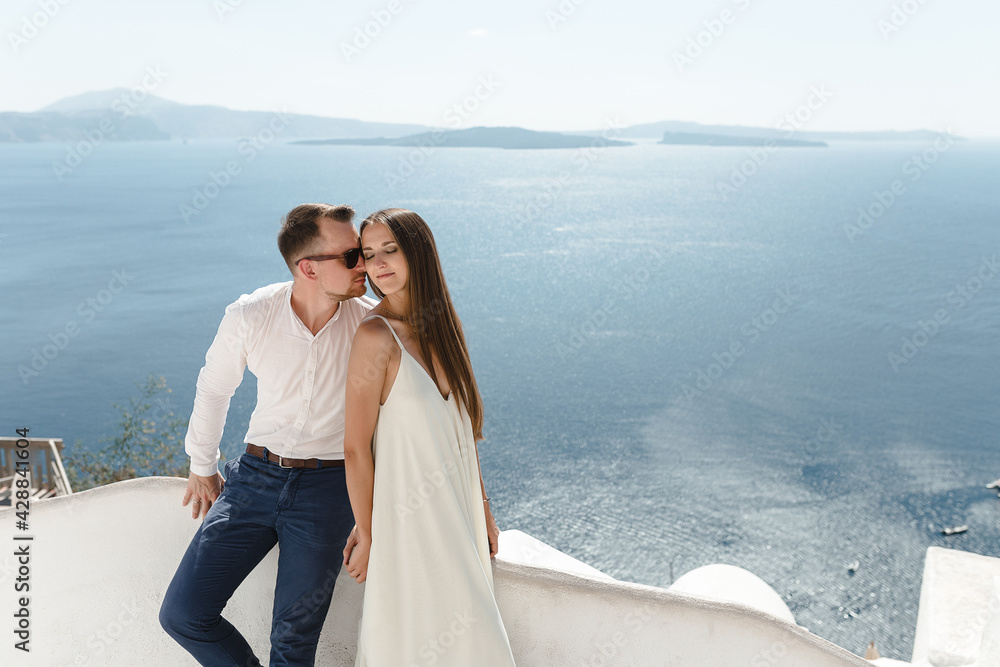 The couple is sitting on the roof in Santorini, hugging and laughing