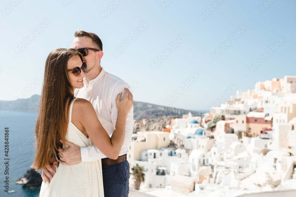 Happy couple hugging and laughing together with a view of Santorini