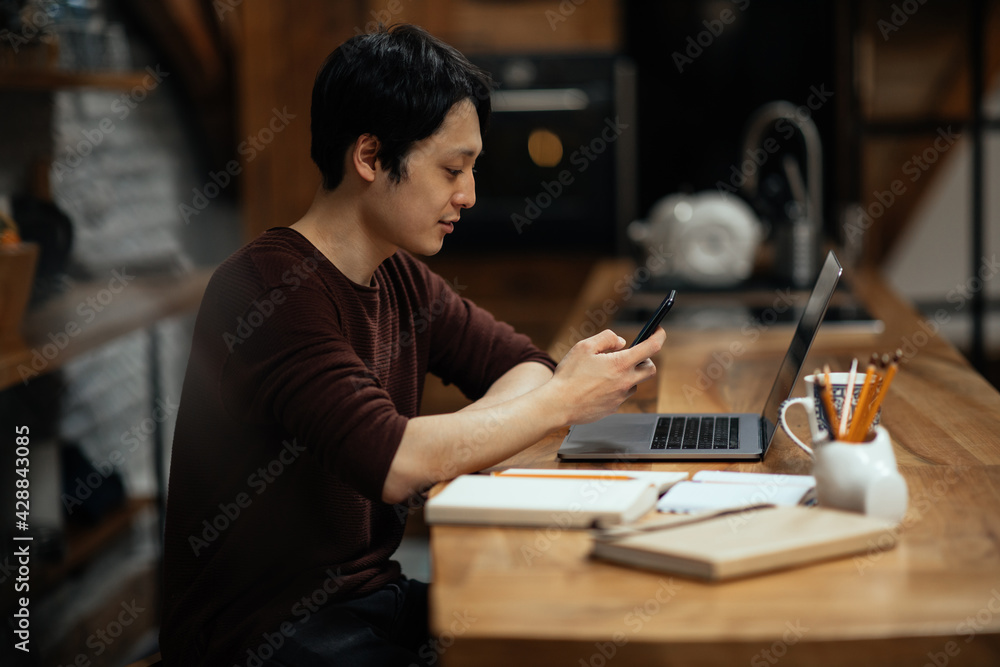 Asian man using smartphone while working at home