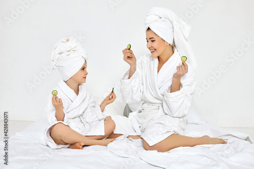 mother and daughter holding fresh cucumber slices