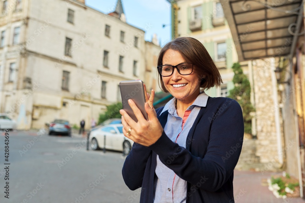 Middle-aged business woman in in cardigan glasses with mobile phone Middle-aged business woman in in cardigan glasses with mobile phone