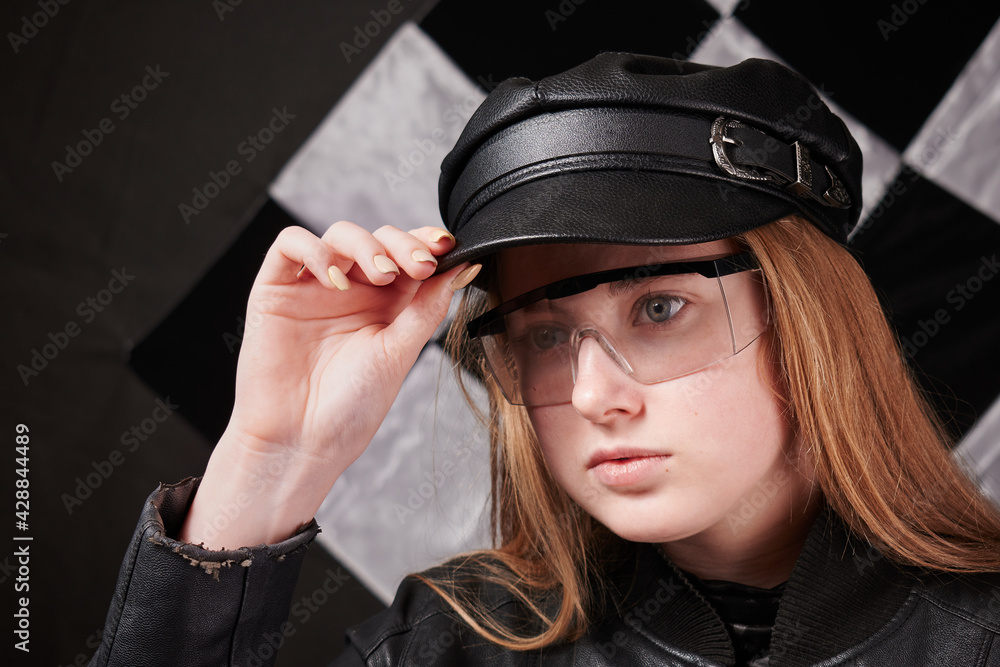 portrait of young girl in leather cap and transparent glasses. checkered black and white background portrait of young girl in leather cap and transparent glasses. checkered black and white background