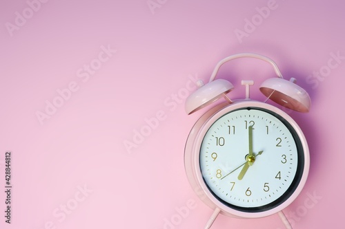 Classic pink alarm clock. Monochrome background image with copyspace. Time, waking up early, deadline, time management and morning routine concept