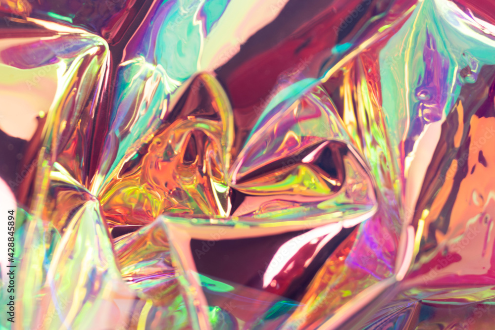 Colorful blurred holographic background. Iridescent wrinkled foil material.