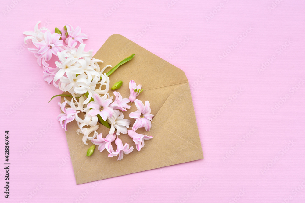 A envelope with hyacinth flowers on pink background. Flat lay, top view.