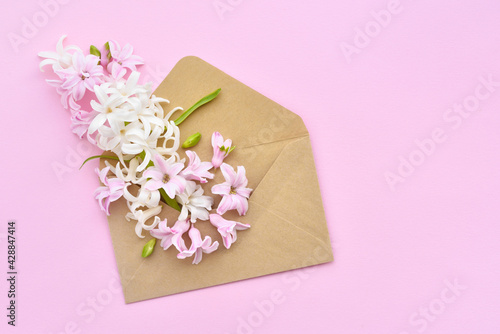 A envelope with hyacinth flowers on pink background. Flat lay, top view. © nmelnychuk