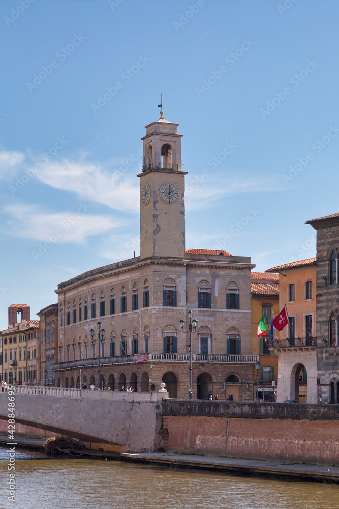 The Palazzo Pretorio and its clock tower next to the Logge Dei Banchi, the Ponte Di Mezzo and the Palazzo Gambacorti in Pisa, Italy