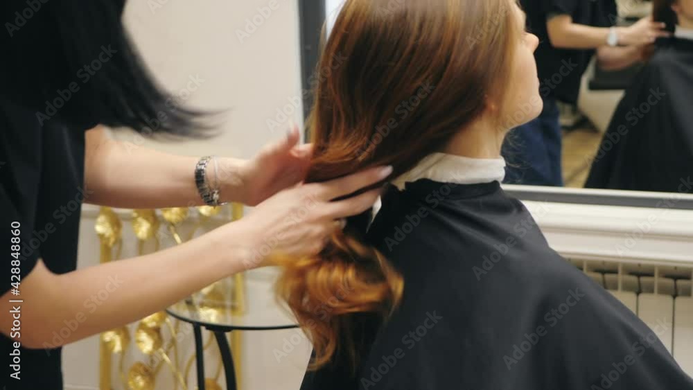 Girl hairdresser makes stylish styling to woman client with red hair with the help of hands. Woman barber work in salon. Girl hairdresser makes stylish styling to woman client with red hair with the help of hands. Woman barber work in salon.