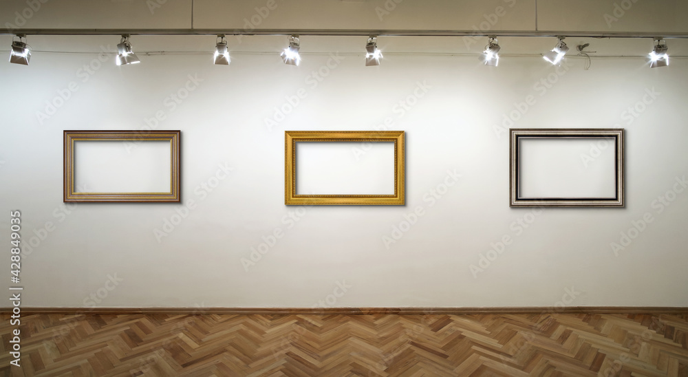 Interior of a white wall with frames and spot lights at art gallery Interior of a white wall with frames and spot lights at art gallery