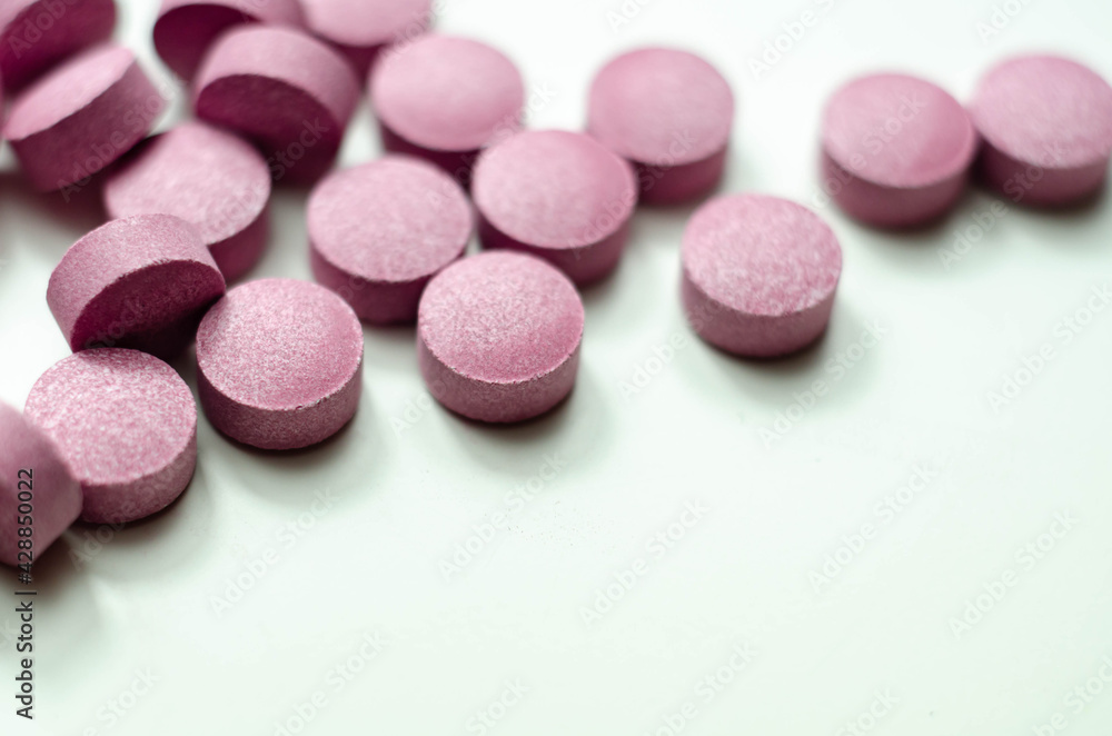Purple pills scattered on a white background, food supplements which includes acai berries